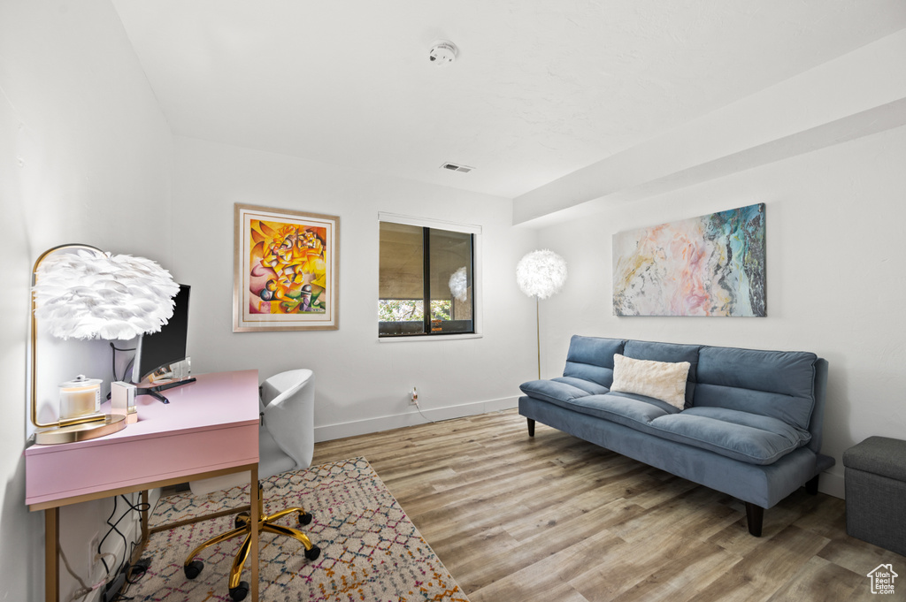 Home office with baseboards, visible vents, and wood finished floors