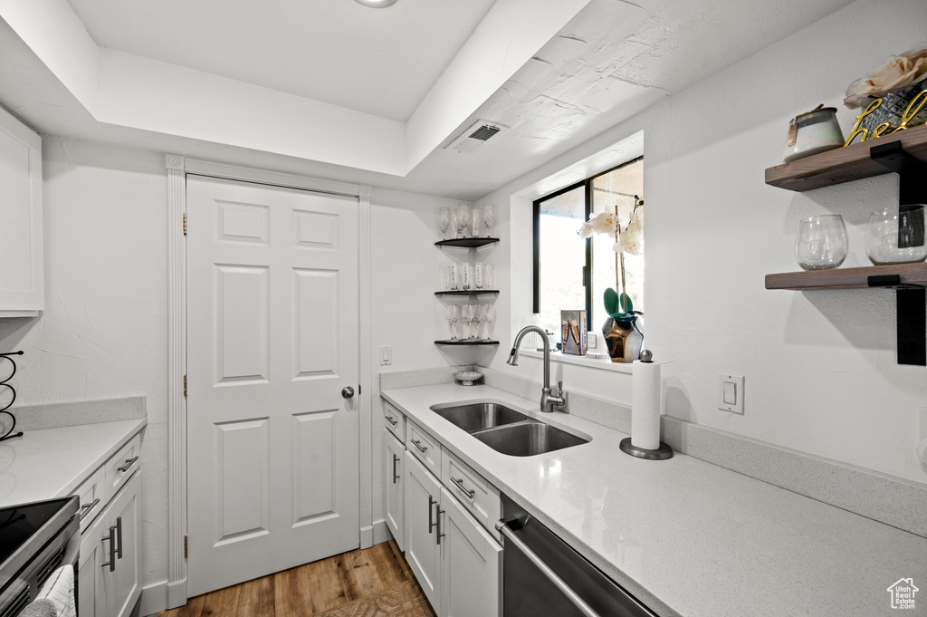 Kitchen with a sink, wood finished floors, open shelves, visible vents, and appliances with stainless steel finishes