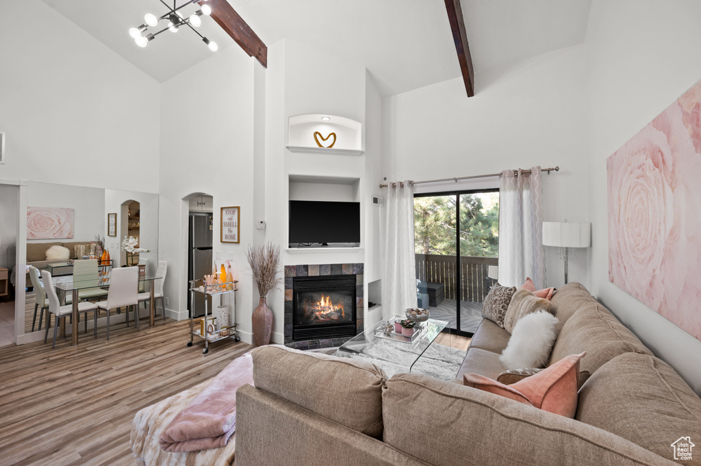 Living area featuring an inviting chandelier, high vaulted ceiling, wood finished floors, a fireplace, and beam ceiling