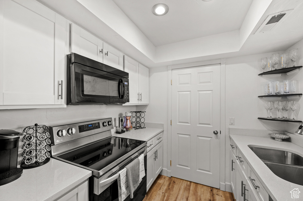 Kitchen with a sink, white cabinets, visible vents, stainless steel electric range oven, and black microwave