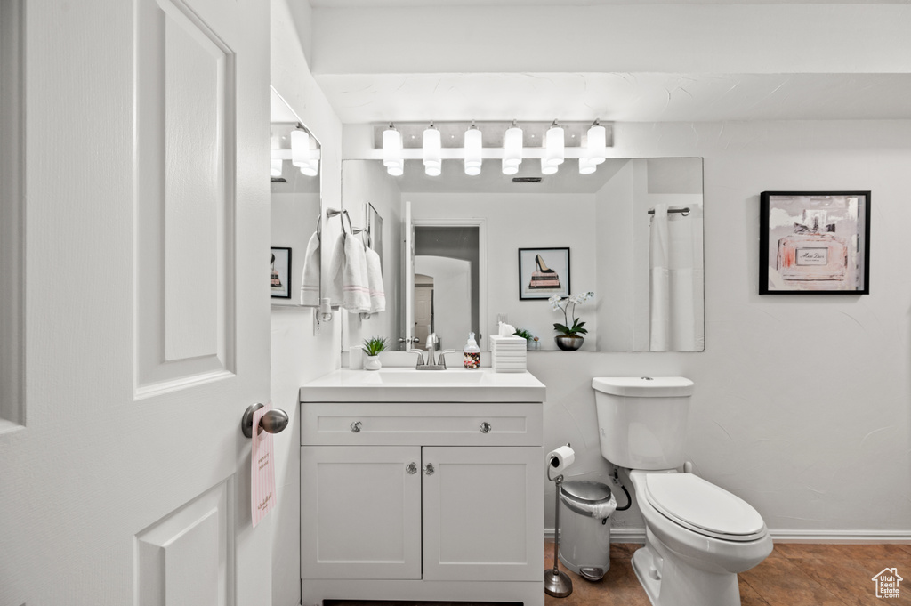 Bathroom featuring toilet, baseboards, and vanity
