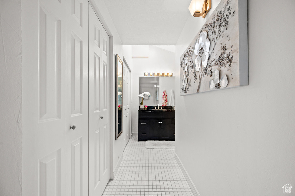 Corridor with a sink, light tile patterned flooring, and baseboards