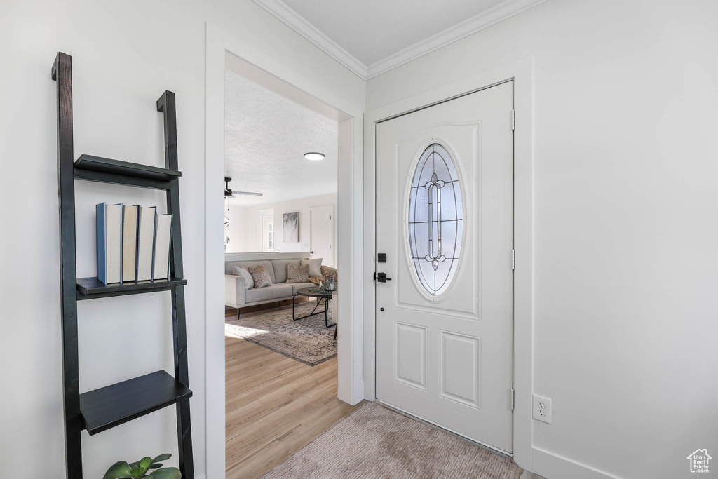 Entryway with crown molding, wood finished floors, and ceiling fan