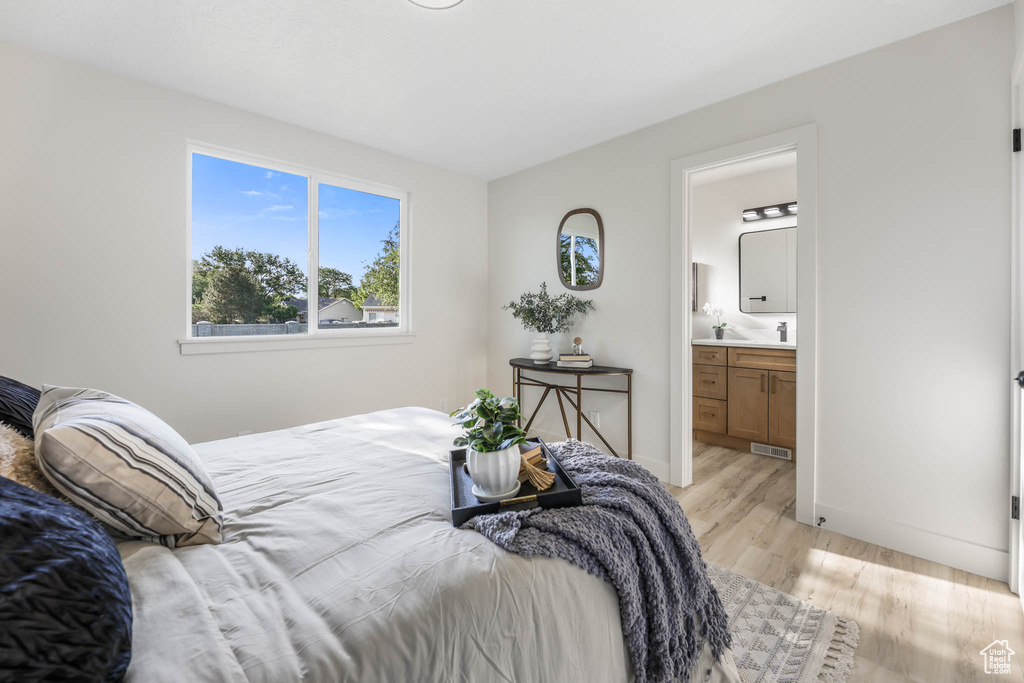 Bedroom featuring light wood-style flooring, baseboards, and connected bathroom