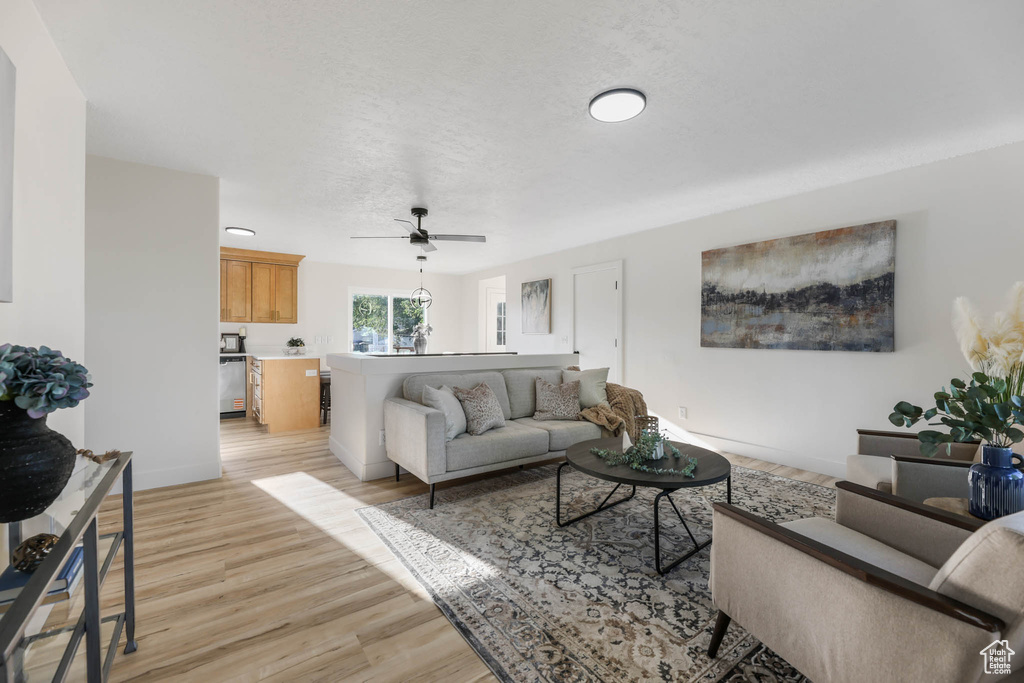 Living room with light wood-type flooring, ceiling fan, and baseboards