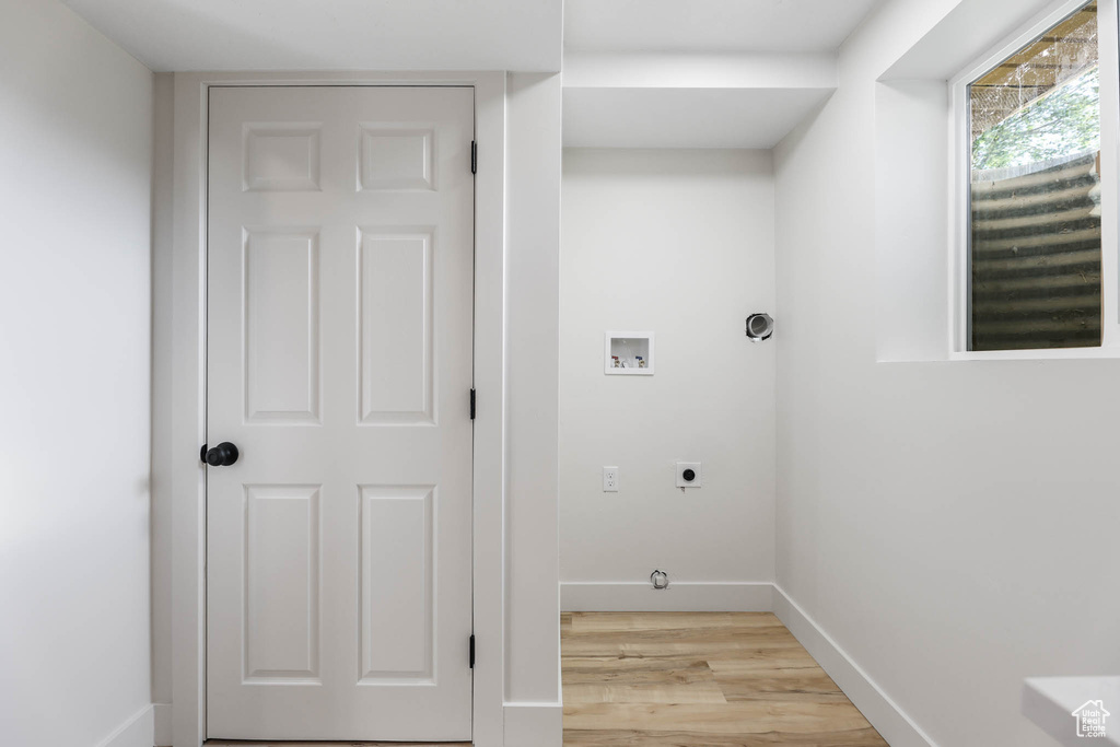 Laundry area with hookup for an electric dryer, washer hookup, light wood finished floors, and baseboards