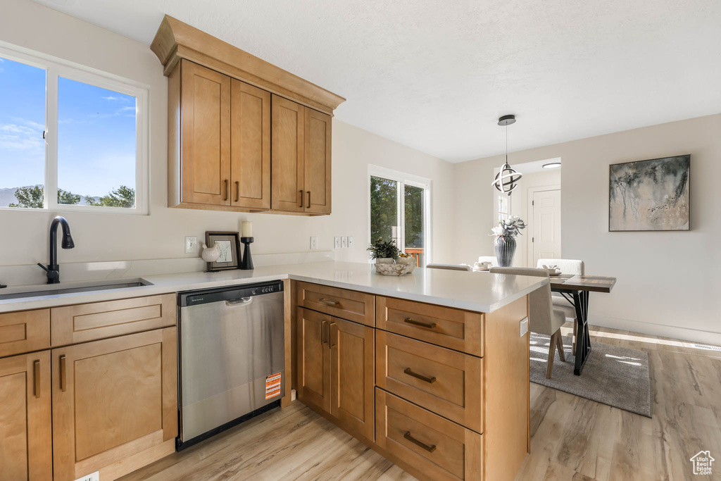 Kitchen featuring dishwasher, a sink, light wood-style floors, and a peninsula
