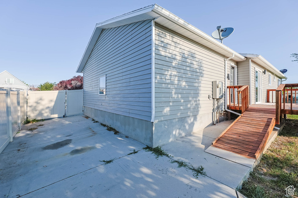 View of property exterior with a patio, a gate, and a deck