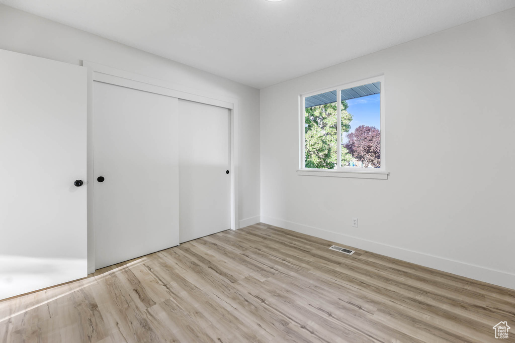Unfurnished bedroom featuring wood finished floors, a closet, and baseboards