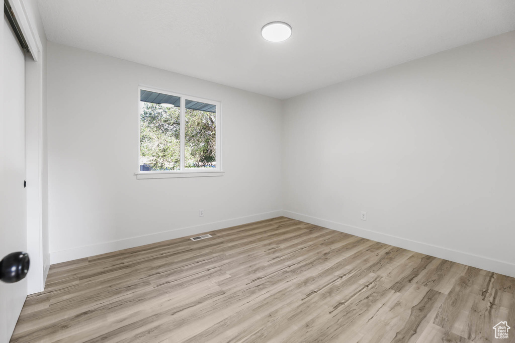 Unfurnished bedroom featuring a closet, light wood-style flooring, and baseboards