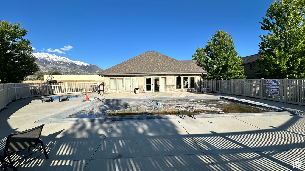 Community pool featuring french doors, a mountain view, a fenced backyard, and a patio