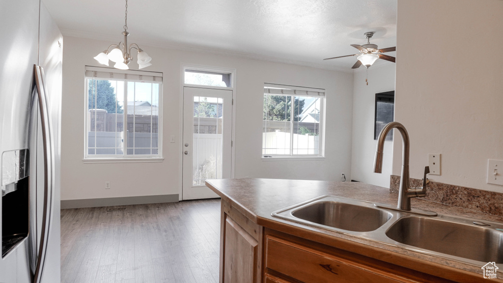 Kitchen with stainless steel refrigerator with ice dispenser, a sink, brown cabinetry, decorative light fixtures, and a chandelier