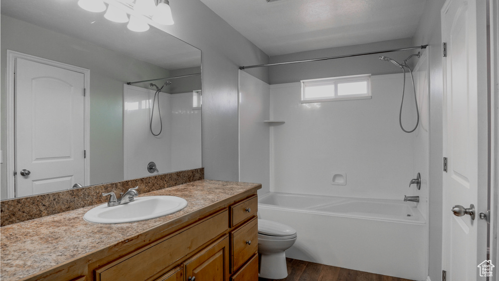 Bathroom featuring wood finished floors, shower / bath combination, toilet, and vanity