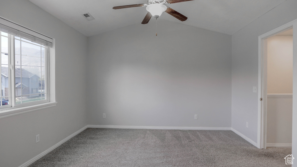 Spare room featuring ceiling fan, carpet floors, baseboards, and vaulted ceiling