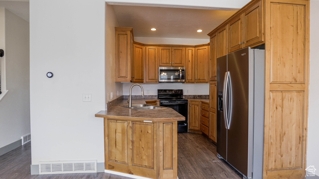 Kitchen with stainless steel appliances, a sink, dark wood finished floors, a peninsula, and recessed lighting