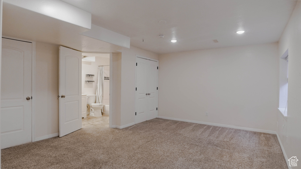 Unfurnished bedroom featuring light carpet, baseboards, ensuite bathroom, and recessed lighting