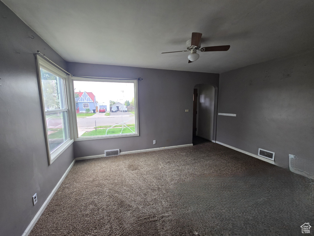 Spare room featuring arched walkways, healthy amount of natural light, carpet, and ceiling fan