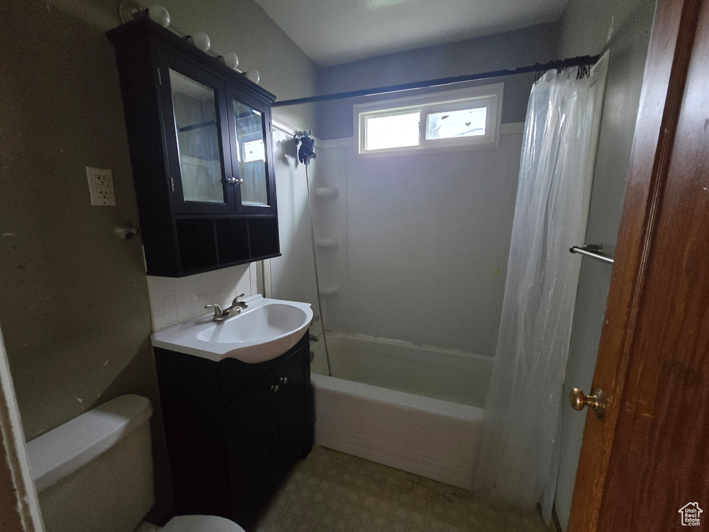 Bathroom with toilet, shower / bath combo with shower curtain, tasteful backsplash, vanity, and tile patterned floors