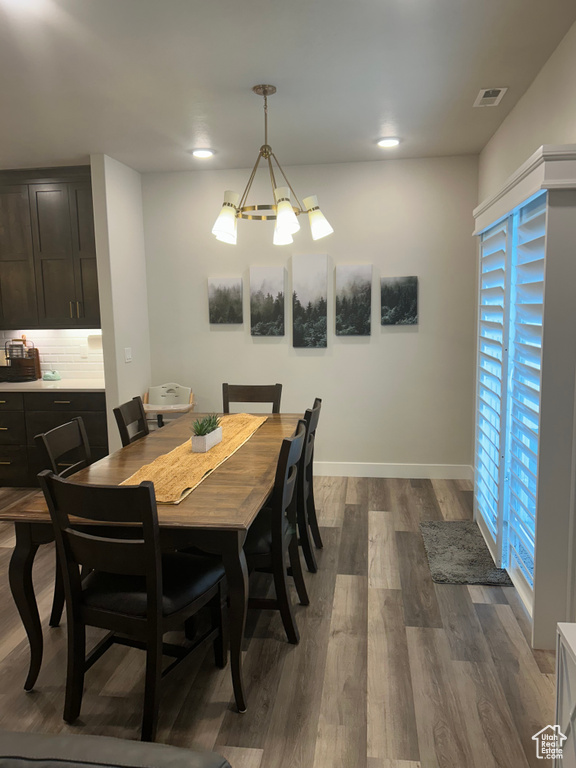 Dining room featuring dark wood finished floors, a chandelier, baseboards, and recessed lighting