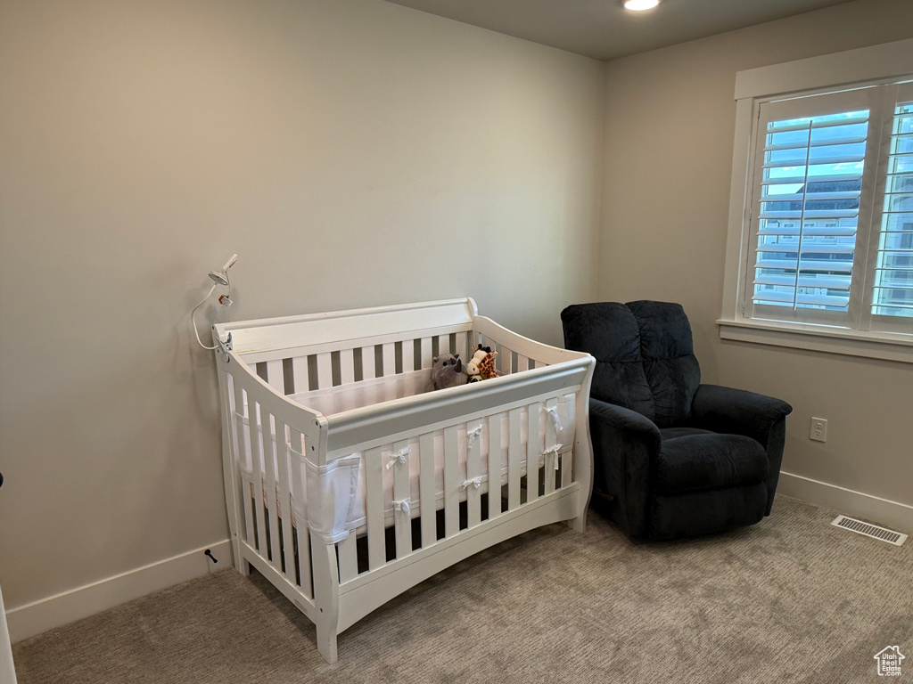 Carpeted bedroom with baseboards and a crib