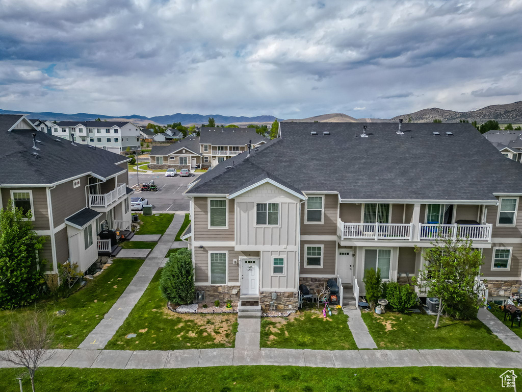 Townhome / multi-family property with a residential view, stone siding, a balcony, roof with shingles, and board and batten siding