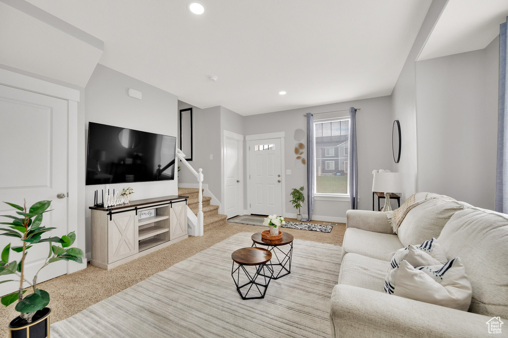 Carpeted living room with stairs, baseboards, and recessed lighting