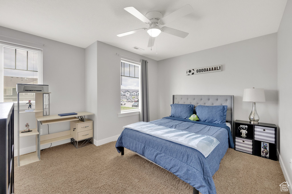 Bedroom with light colored carpet, ceiling fan, and baseboards