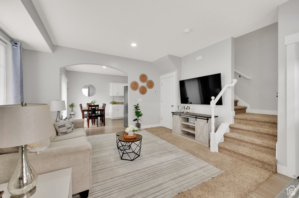 Living area featuring arched walkways, baseboards, stairs, and recessed lighting