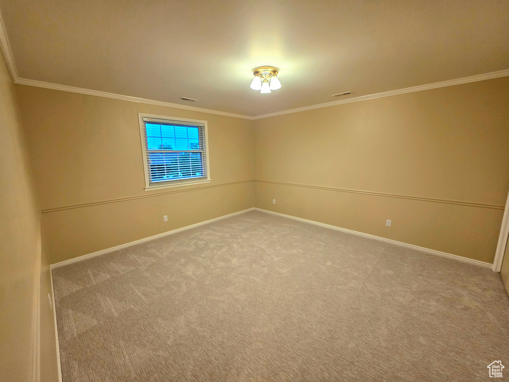 Carpeted spare room featuring baseboards and crown molding