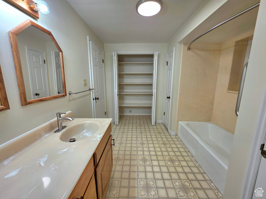 Bathroom featuring tile patterned floors, vanity, a walk in closet, and shower / washtub combination