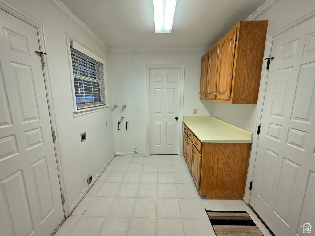 Clothes washing area with cabinet space, hookup for an electric dryer, light tile patterned floors, ornamental molding, and hookup for a washing machine