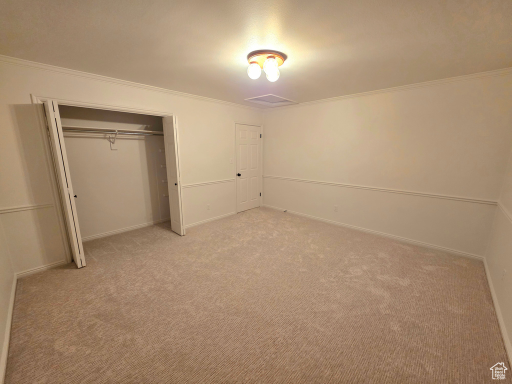 Unfurnished bedroom featuring ornamental molding, light carpet, a closet, and baseboards