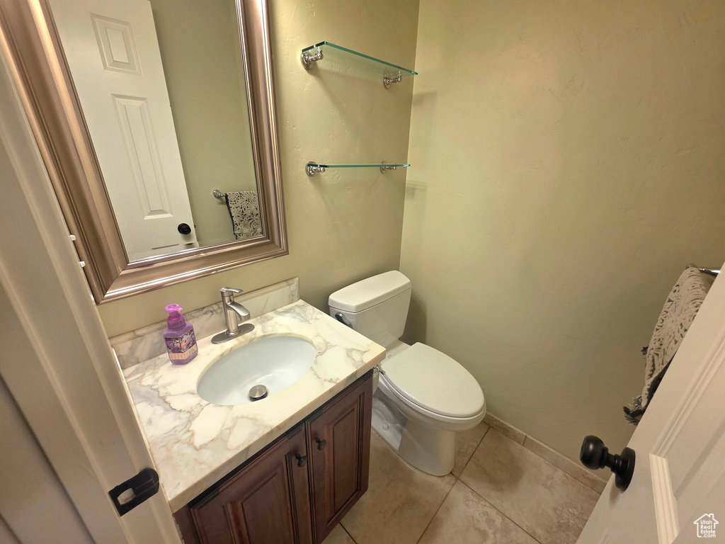 Bathroom featuring toilet, vanity, tile patterned floors, and baseboards