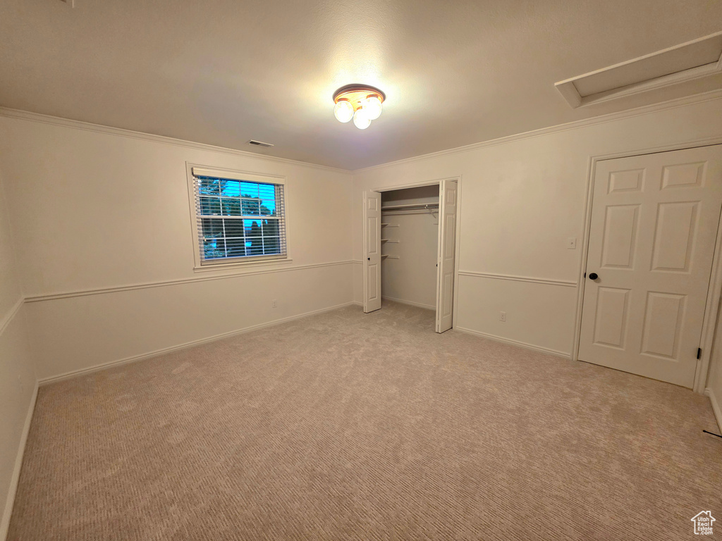 Unfurnished bedroom featuring ornamental molding, light carpet, baseboards, and a closet