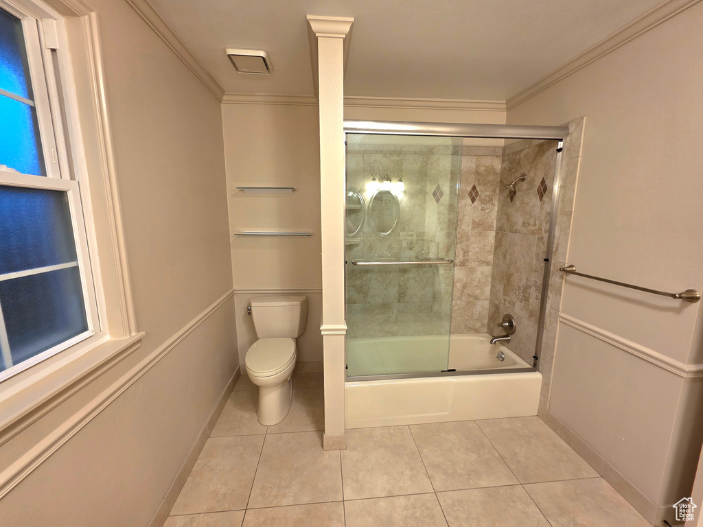 Bathroom featuring tile patterned flooring, toilet, bath / shower combo with glass door, and crown molding