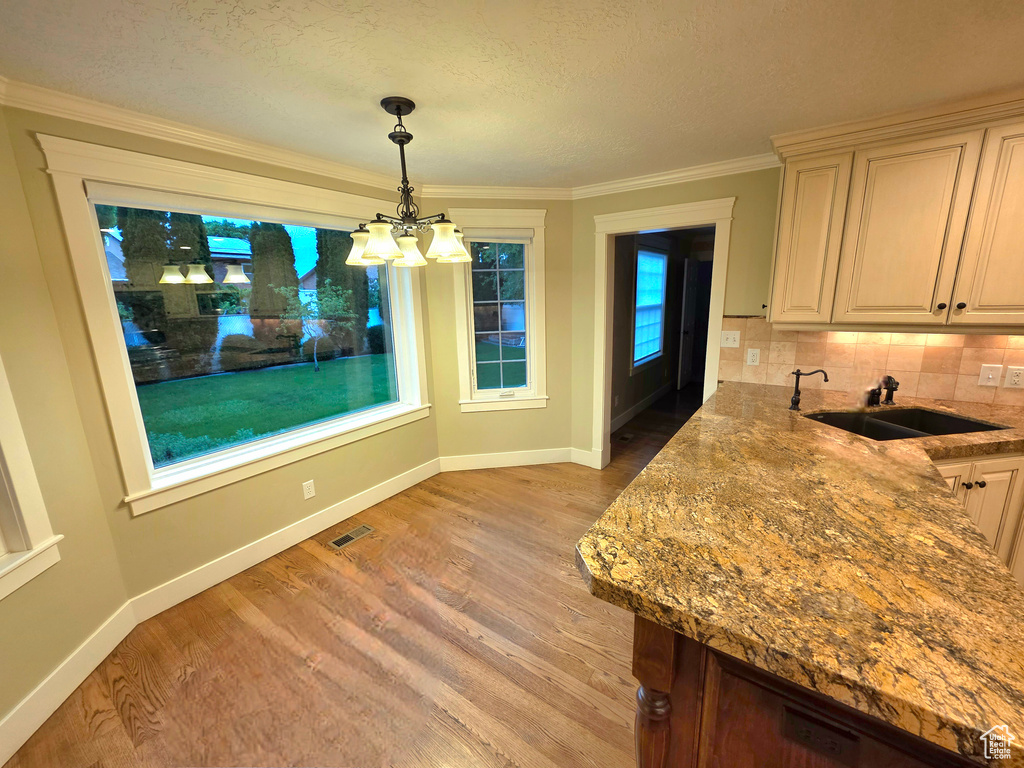 Dining space with a chandelier, light wood finished floors, baseboards, crown molding, and a textured ceiling