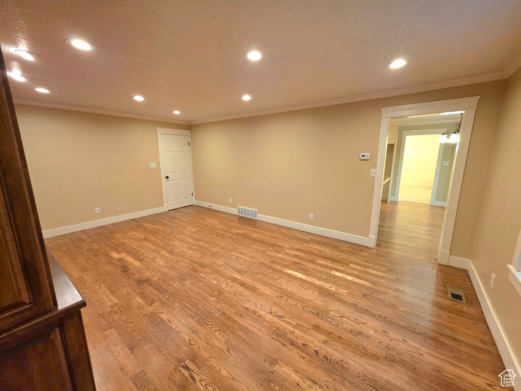 Empty room featuring ornamental molding, recessed lighting, light wood finished floors, and baseboards