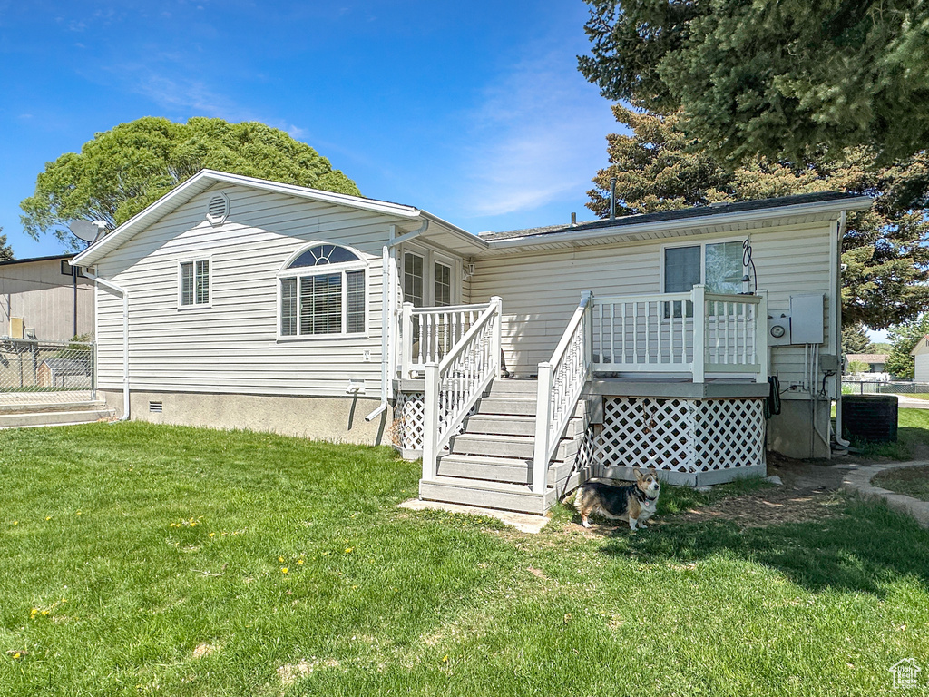 Rear view of house with a wooden deck, a lawn, central air condition unit, stairs, and crawl space