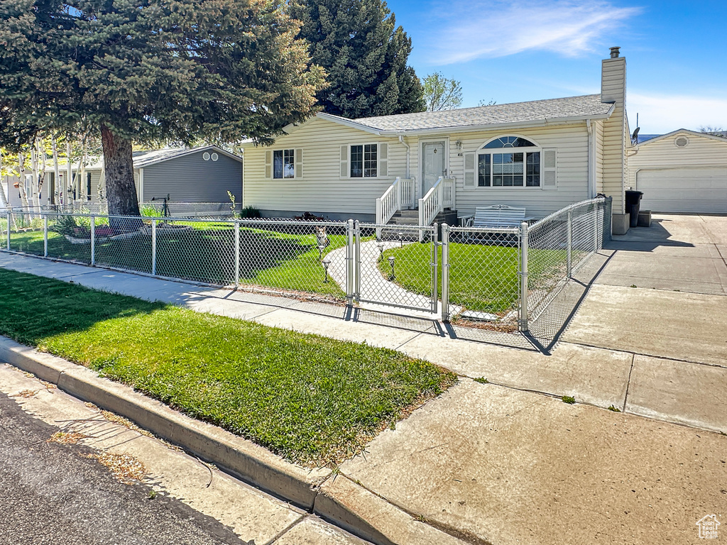 View of front of property with a chimney, a gate, an outbuilding, concrete driveway, and a garage