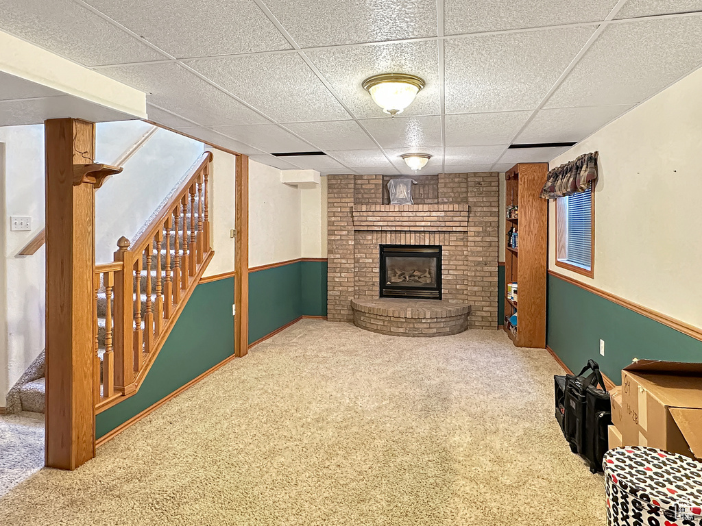 Finished basement with stairway, a brick fireplace, carpet flooring, and a drop ceiling
