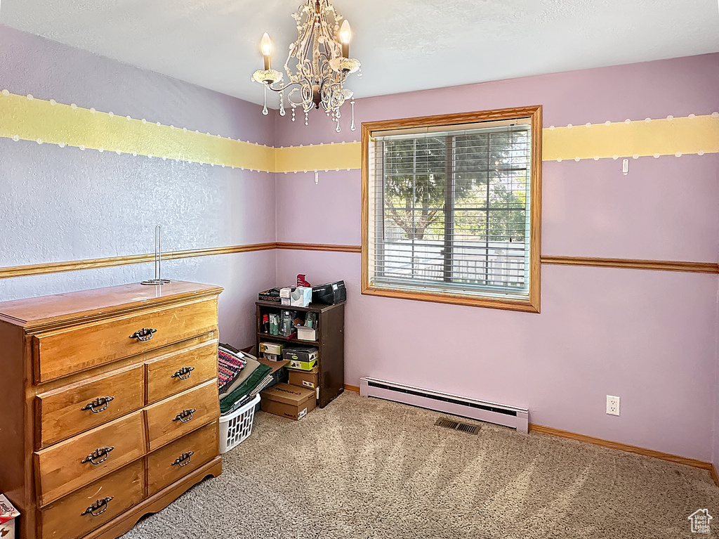 Carpeted bedroom with a baseboard heating unit, a chandelier, and baseboards