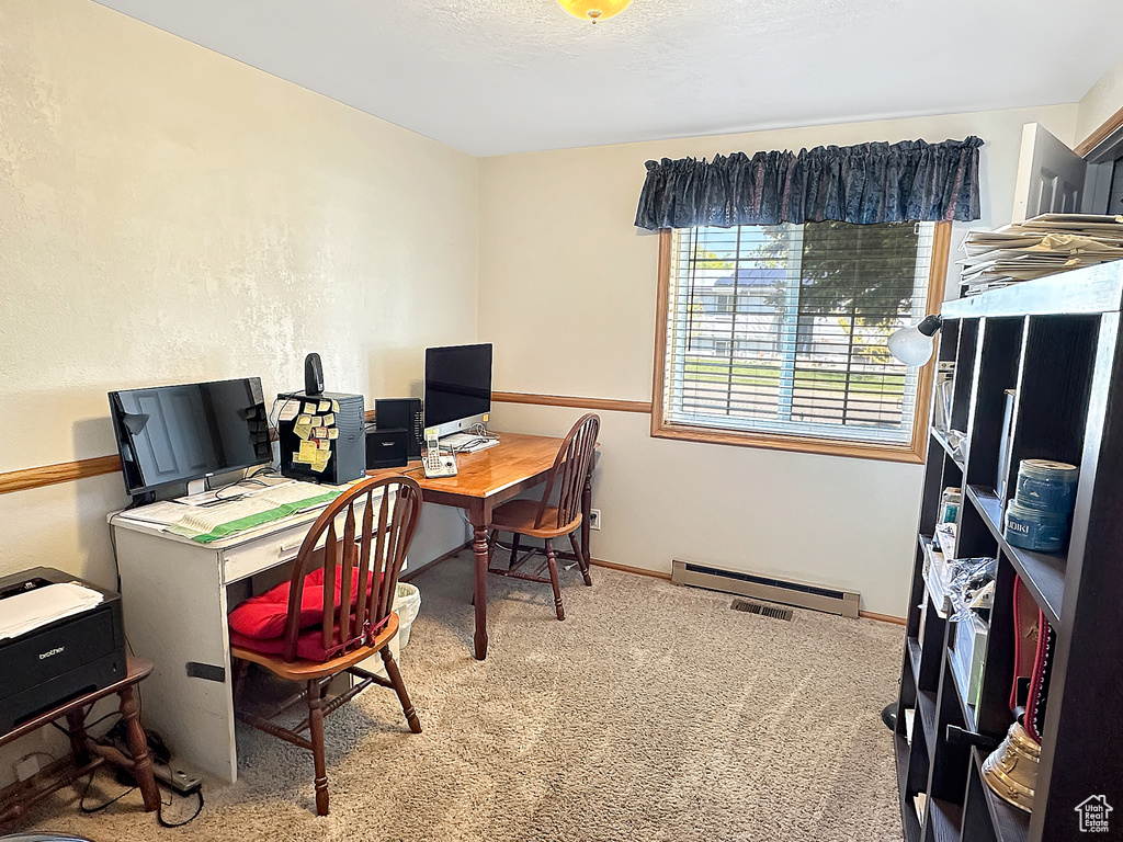 Carpeted office featuring a baseboard radiator and baseboards