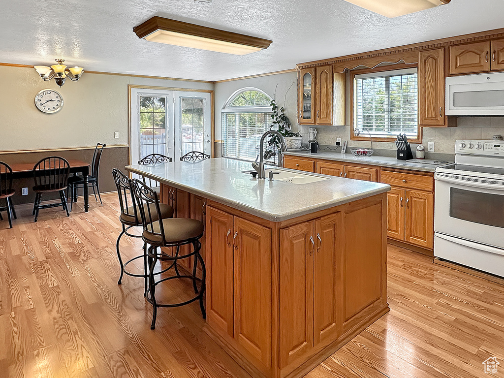 Kitchen featuring white appliances, a sink, a textured ceiling, light wood-style floors, and light countertops