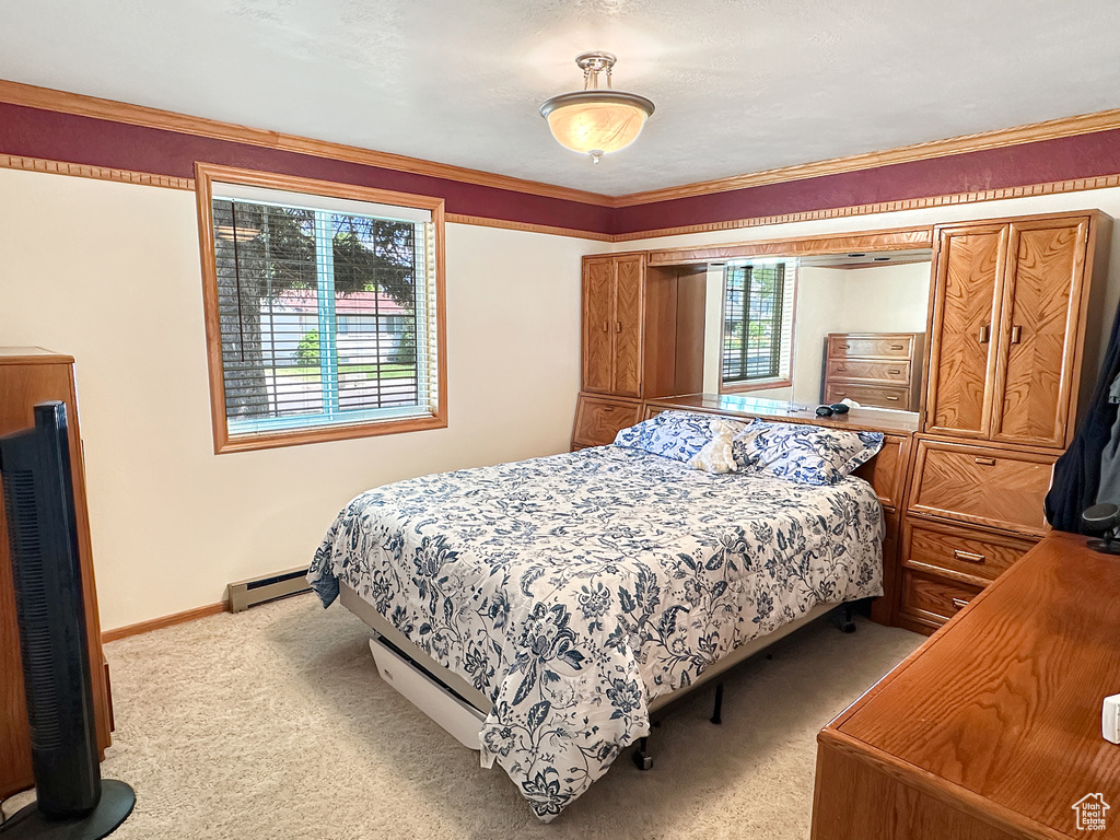 Bedroom with light carpet, a baseboard radiator, baseboards, and crown molding