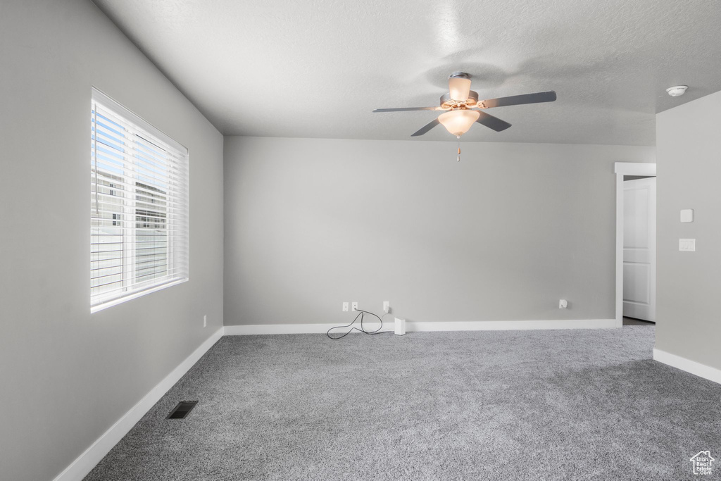 Spare room with ceiling fan, carpet, baseboards, a textured ceiling, and a smoke detector