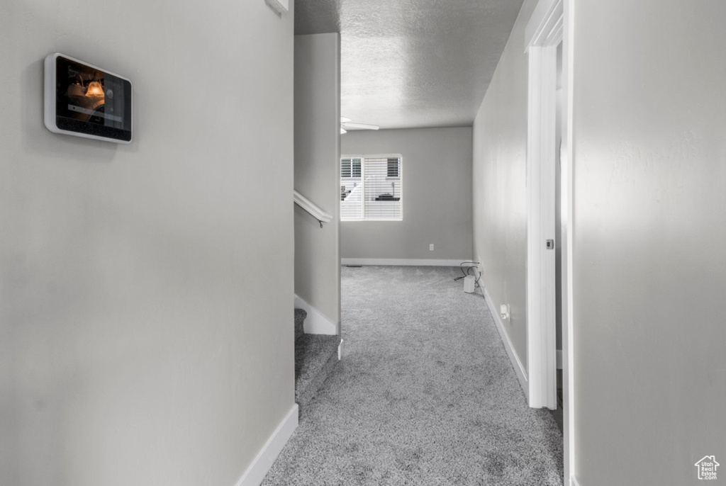 Hallway featuring carpet floors, a textured ceiling, and baseboards
