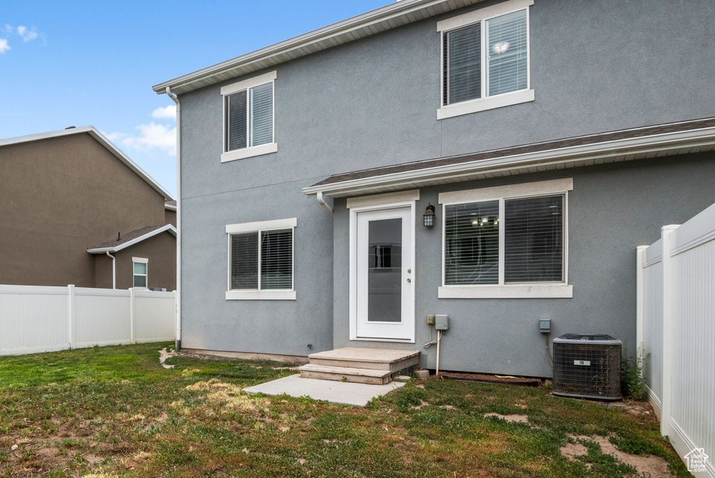 Rear view of house featuring cooling unit and stucco siding