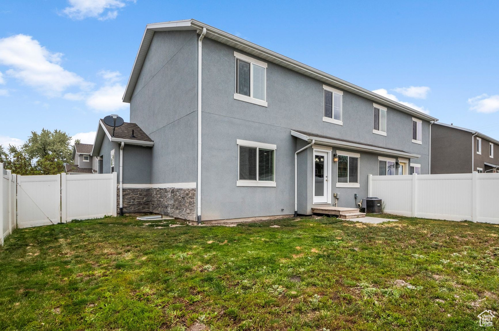 Rear view of property with stucco siding, central AC, and a gate