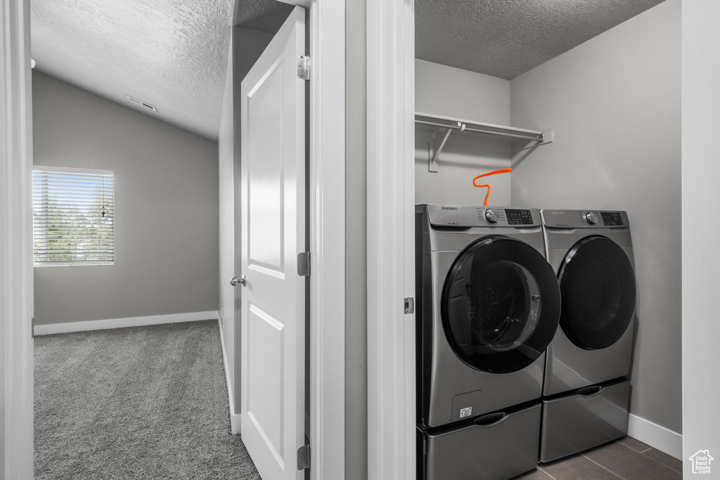 Laundry area featuring a textured ceiling, washing machine and dryer, and baseboards