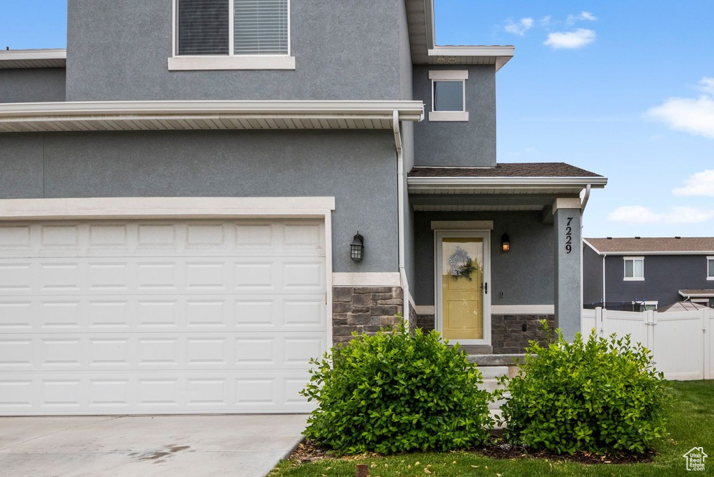 Townhome / multi-family property featuring stucco siding, stone siding, an attached garage, and fence